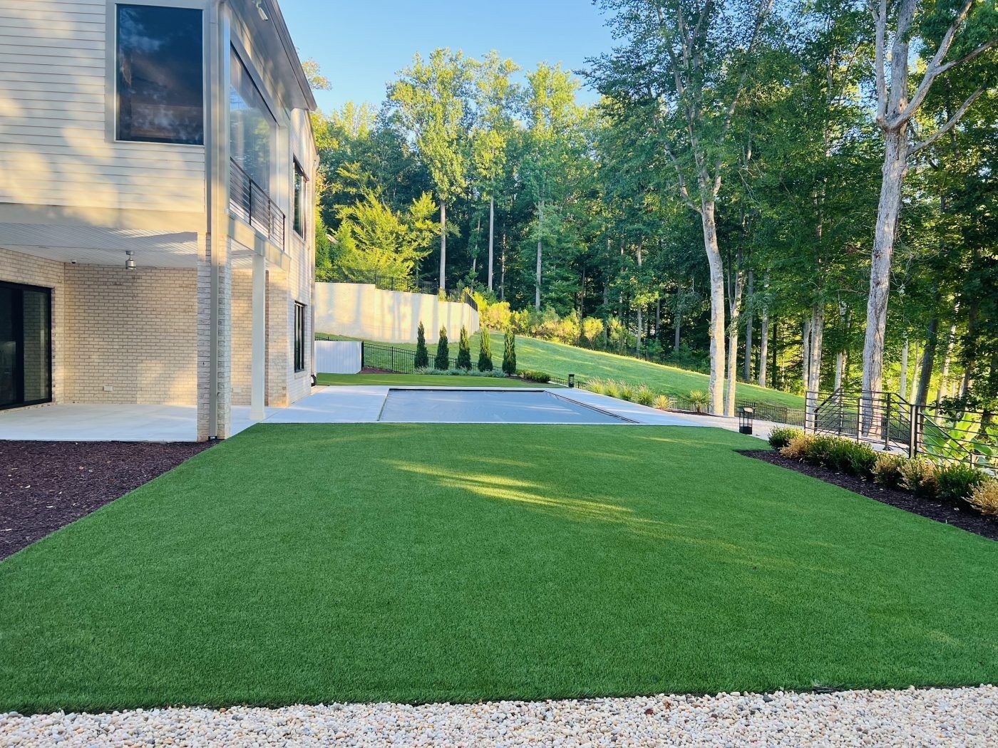 A large lawn in front of a house with trees in the background