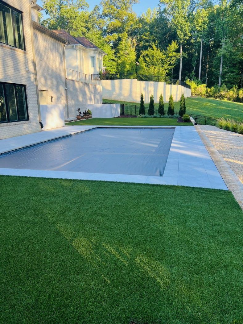 There is a large swimming pool in the backyard of a house