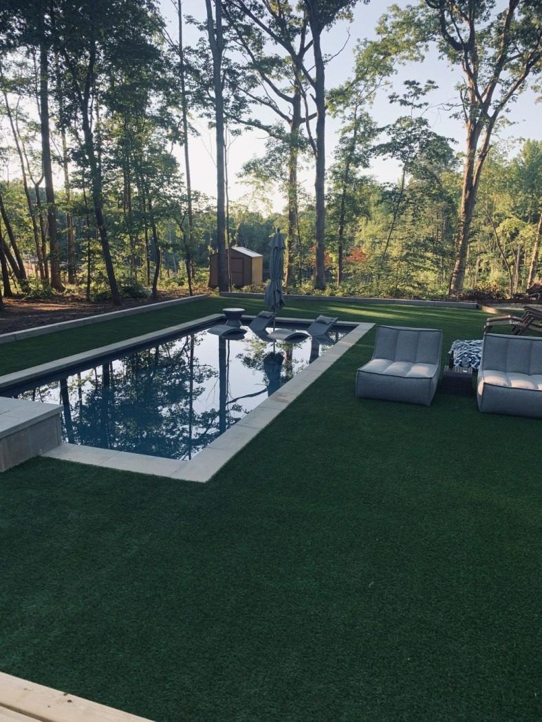 A large swimming pool surrounded by chairs and trees in a backyard