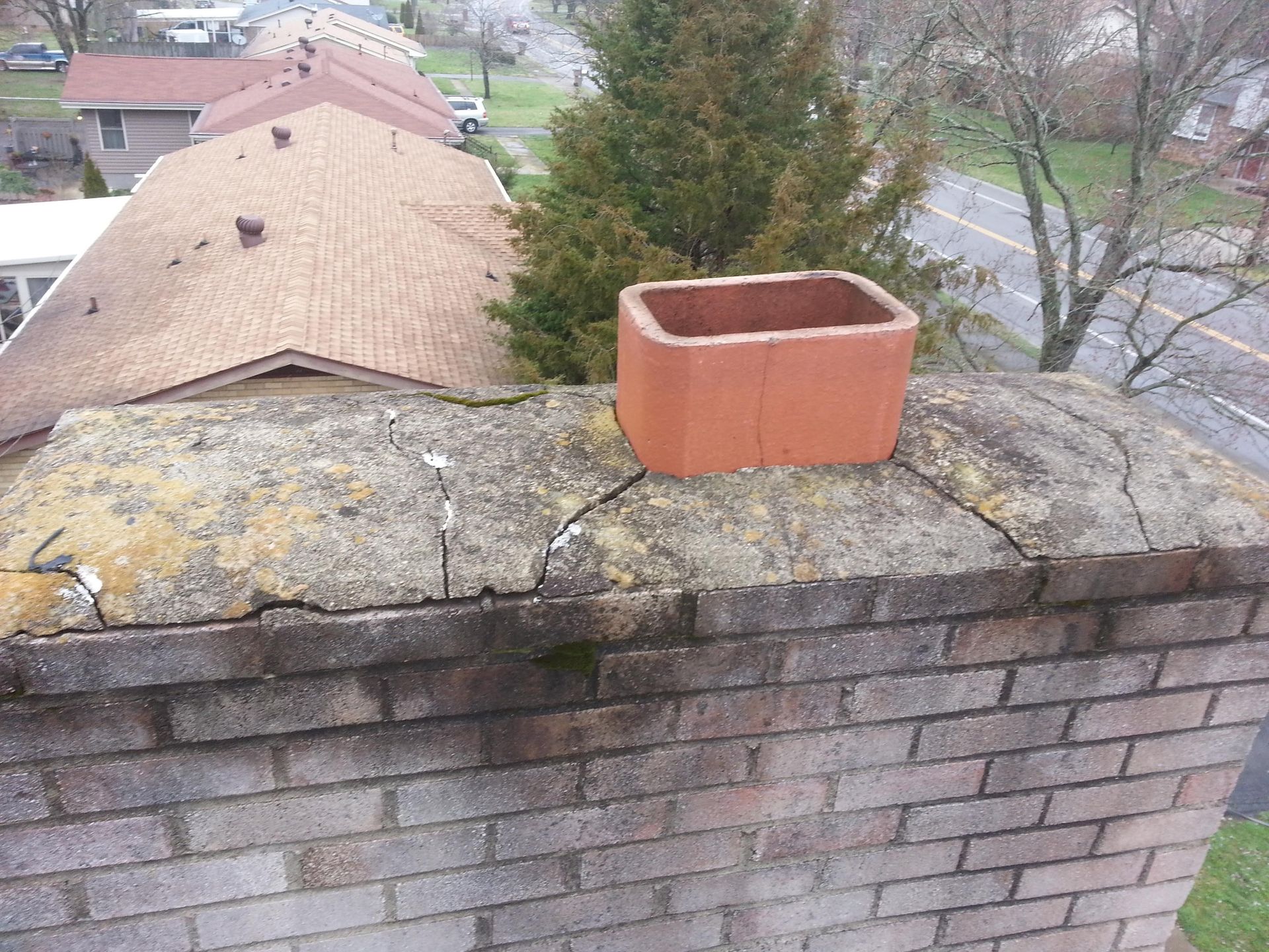 A brick chimney is sitting on top of a brick wall.
