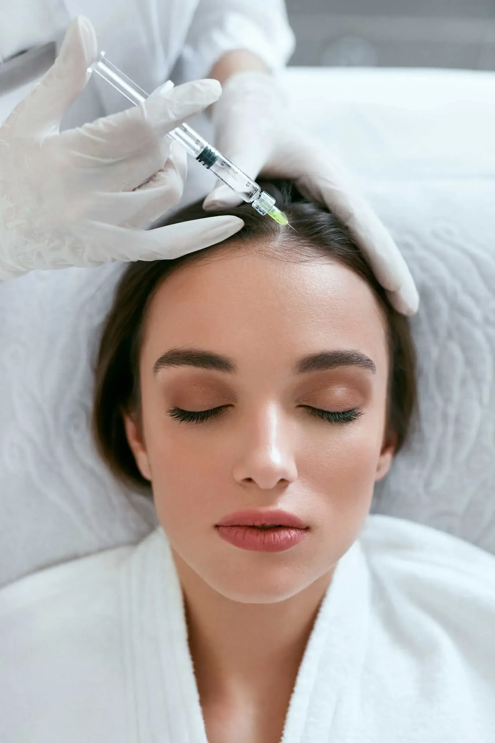Eine Frau bekommt eine Botox-Injektion in den Kopf.
