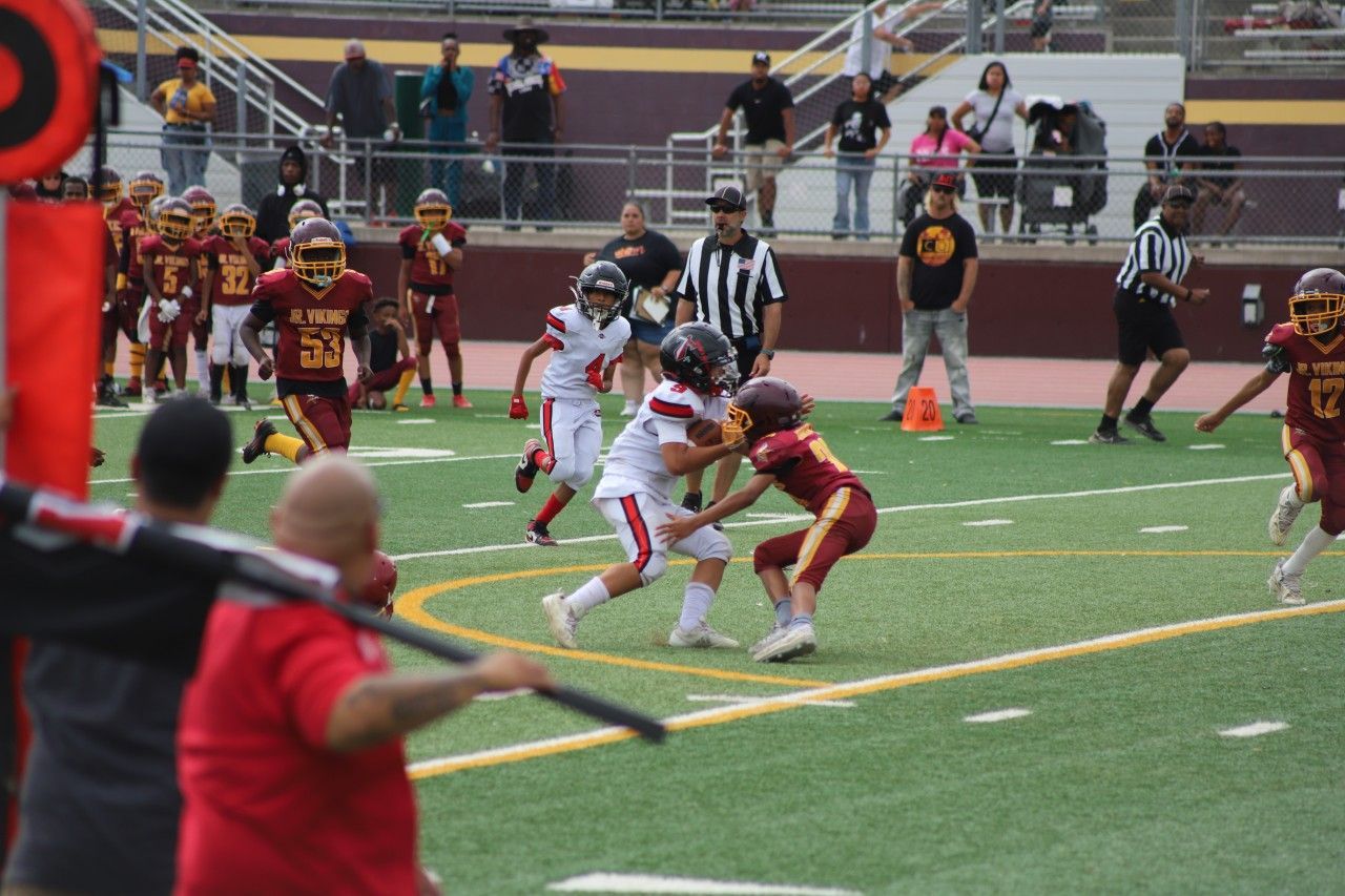 Football player in silver uniform runs with ball on a green field.