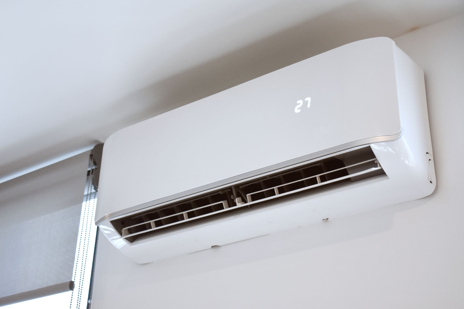 White wall-mounted air conditioning unit with a digital temperature display showing 