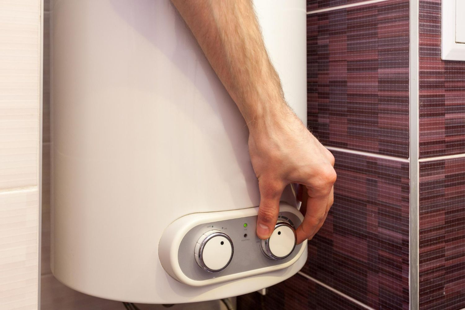 A person is adjusting a water heater in a bathroom.