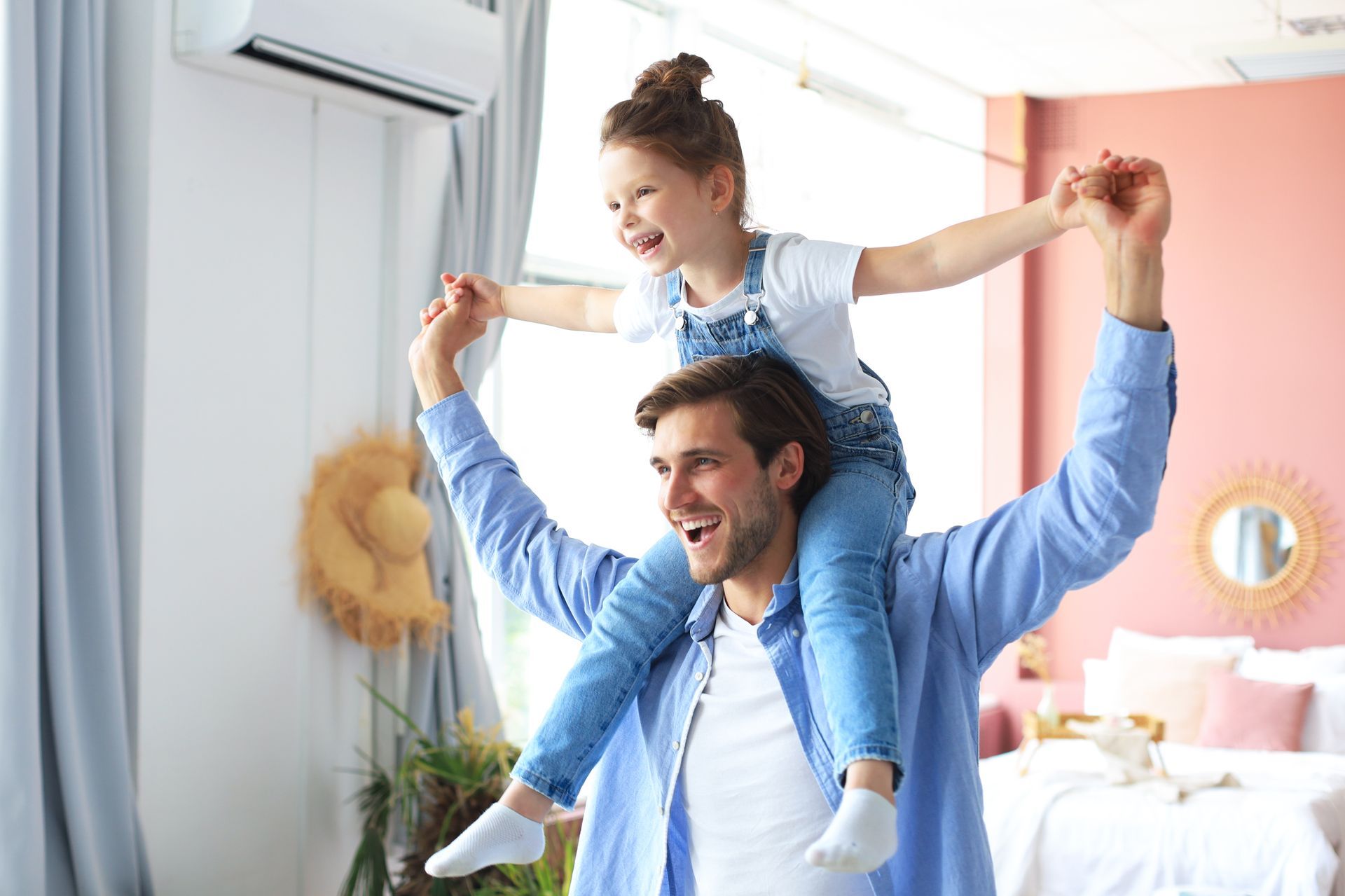 Smiling man giving a child a piggyback ride in a bright bedroom