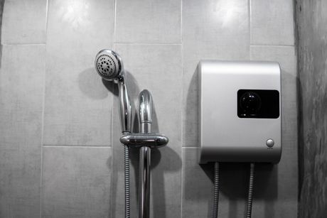a black and white photo of a shower head and a water heater in a bathroom .