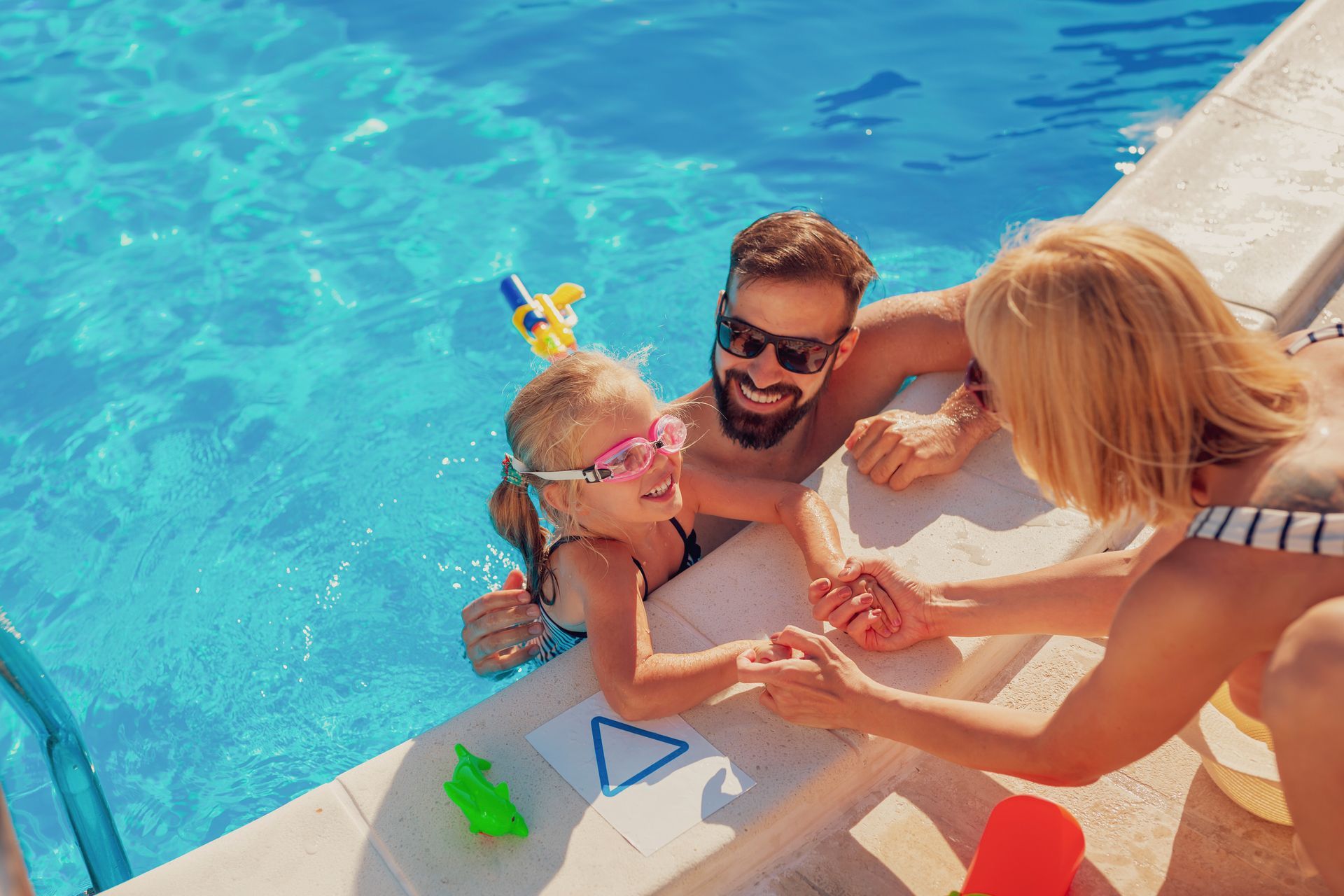 a family is playing in a swimming pool .