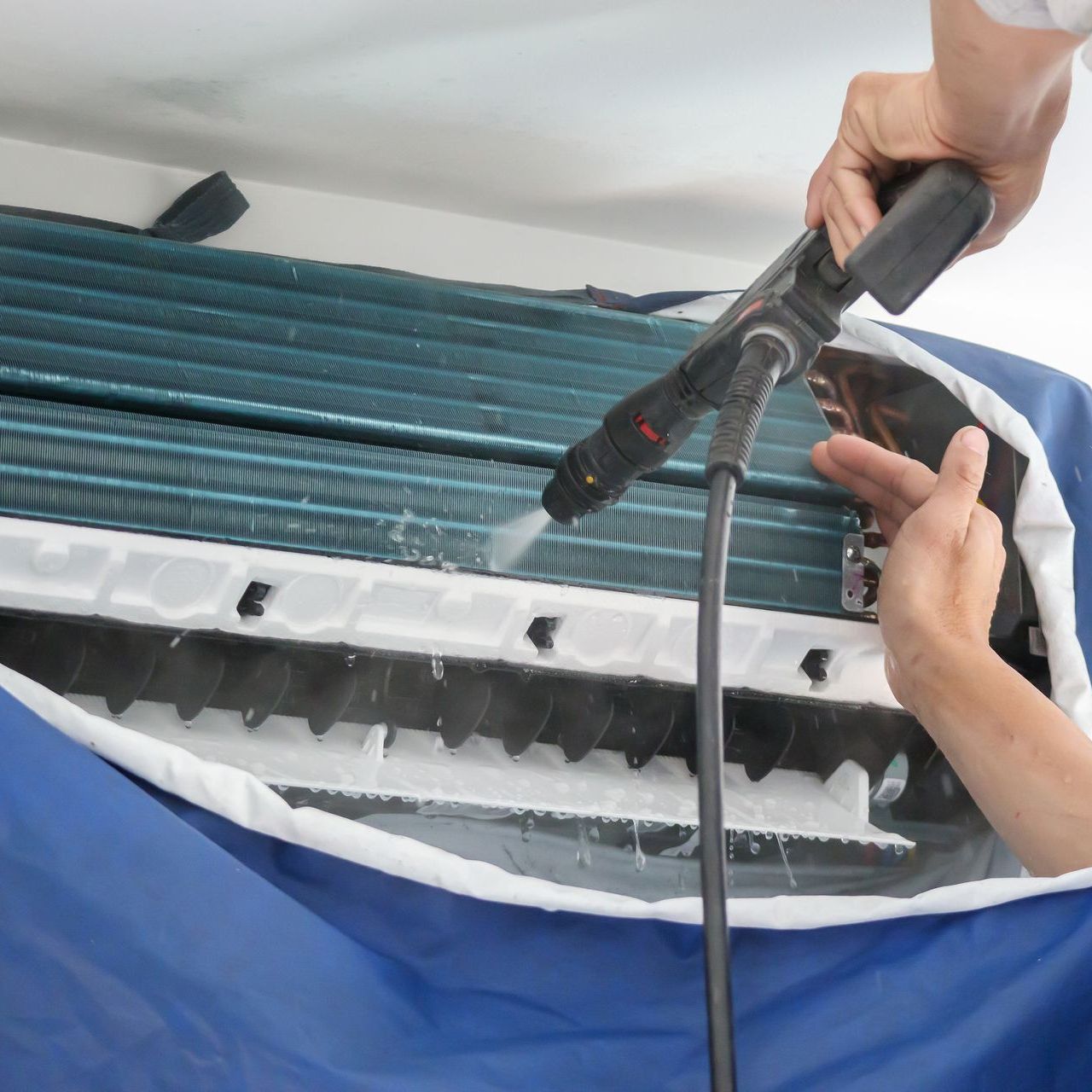 a person is cleaning an air conditioner with a vacuum cleaner .