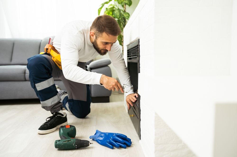 A man is fixing a fireplace in a living room.