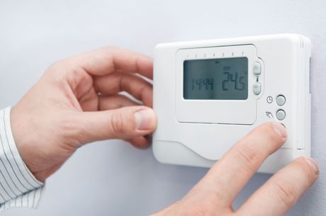 a person is using a thermostat to set the temperature to 24 degrees