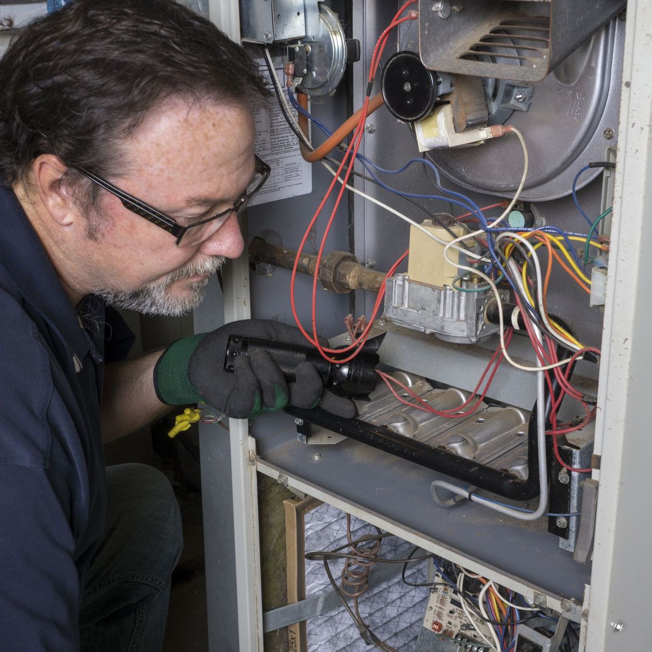 a man is working on a furnace with a screwdriver .