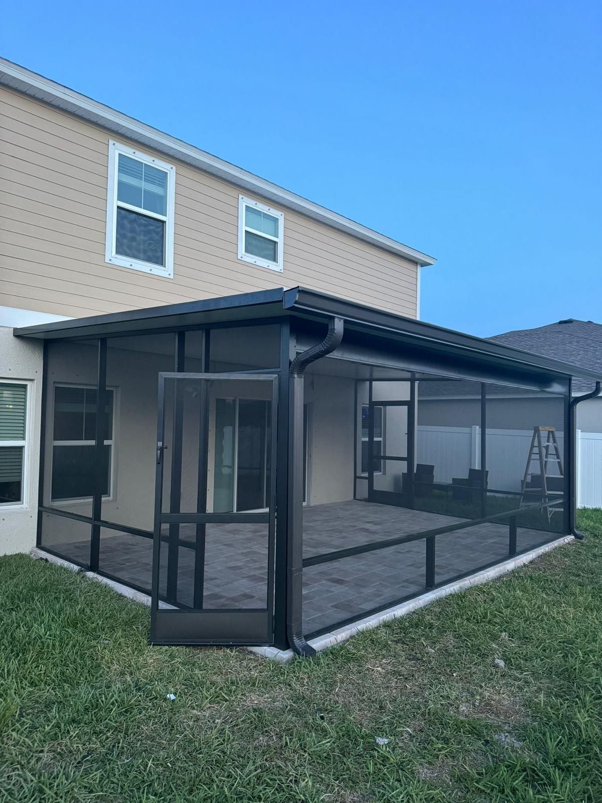 Sunroom with a glass roof and walls, furnished with a dining table, chairs, and a grill.
