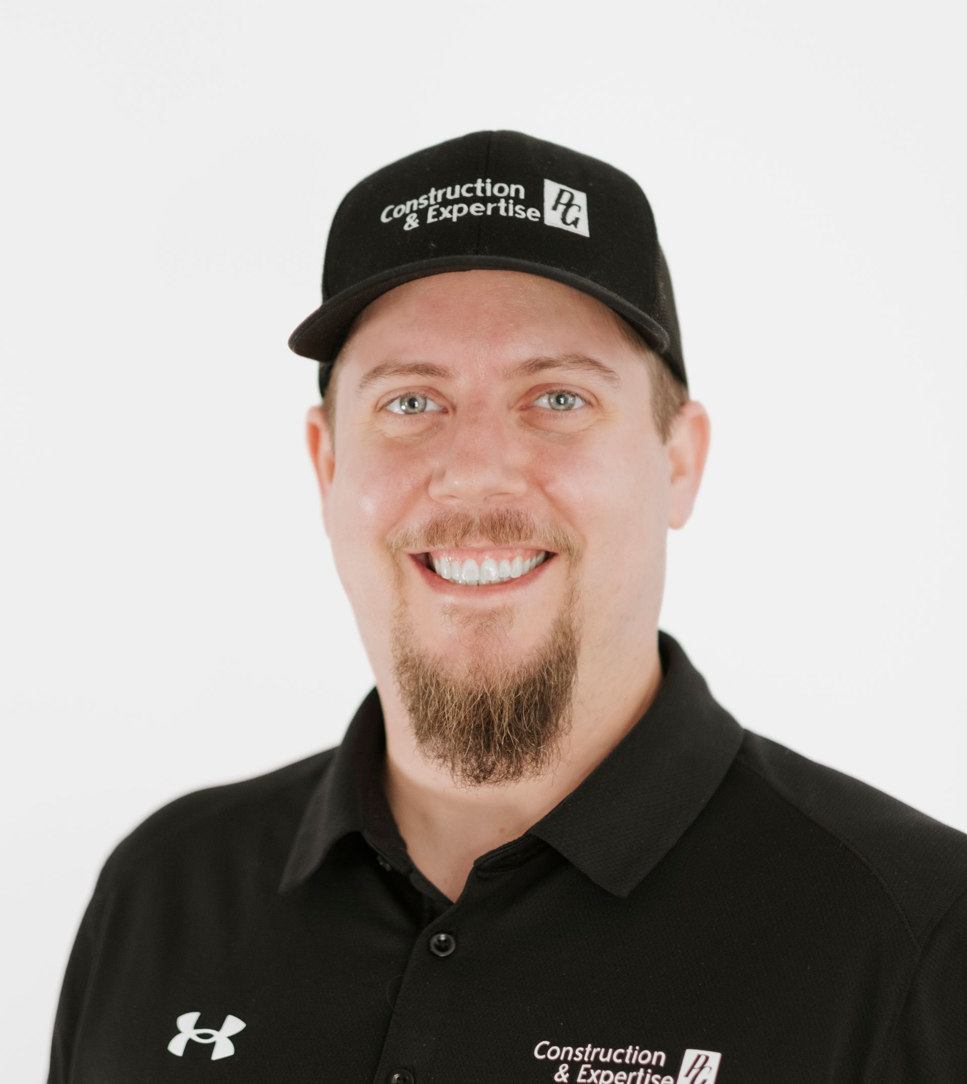 Personne souriante portant une casquette et un polo noirs sur fond blanc