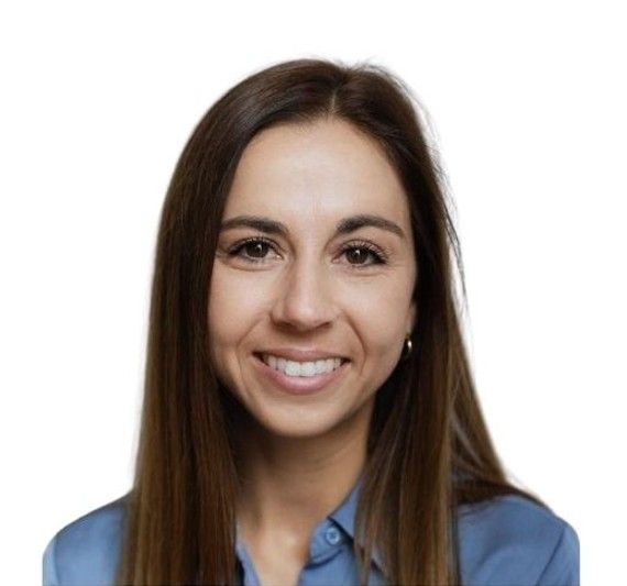 Femme souriante aux longs cheveux bruns, vêtue d'une chemise bleue, sur fond blanc.