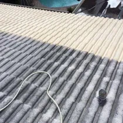 A roof half cleaned, showing a color difference, with a white cable and vent pipe.