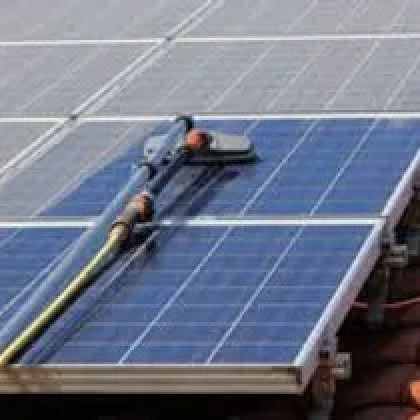 Cleaning solar panels with a long-handled brush.
