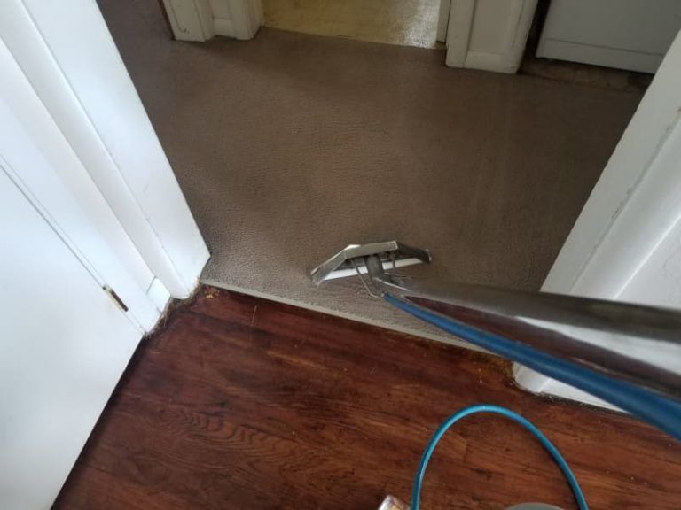 A vacuum cleaner is being used to clean a carpet in a room