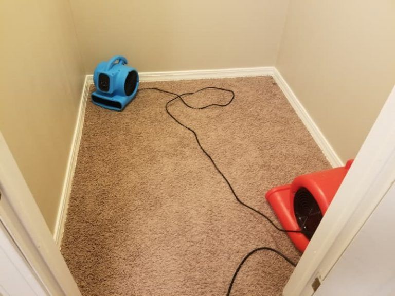 An empty room with a blue fan on the floor