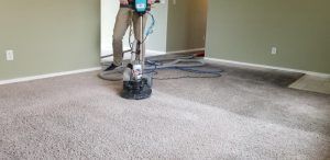 A man is cleaning a carpet with a machine in a living room.