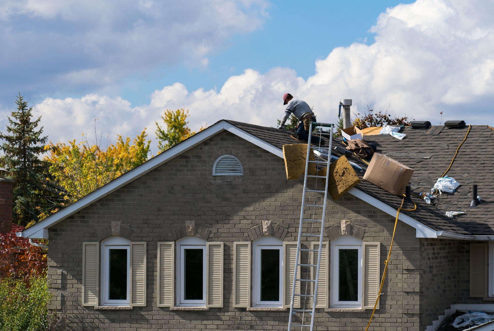 Professional contractor performing emergency roofing repairs on a damaged residential shingle roof.