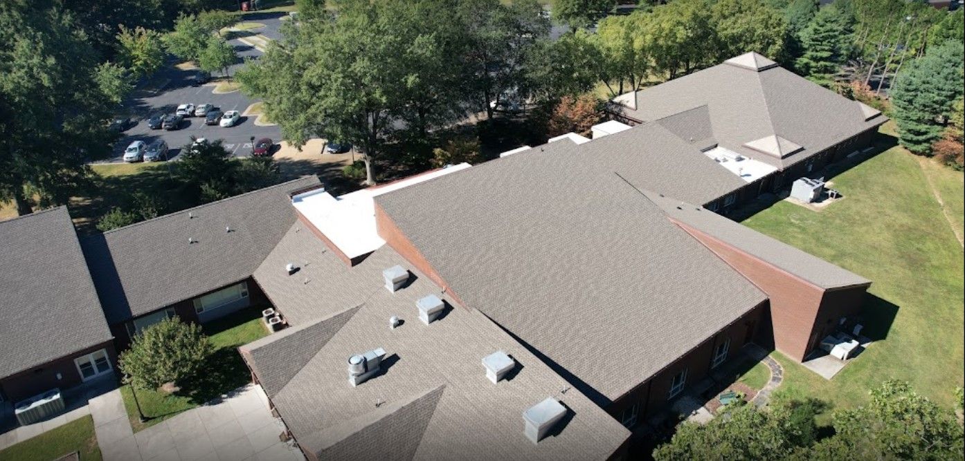 An aerial view of a large building with a lot of roofs surrounded by trees.