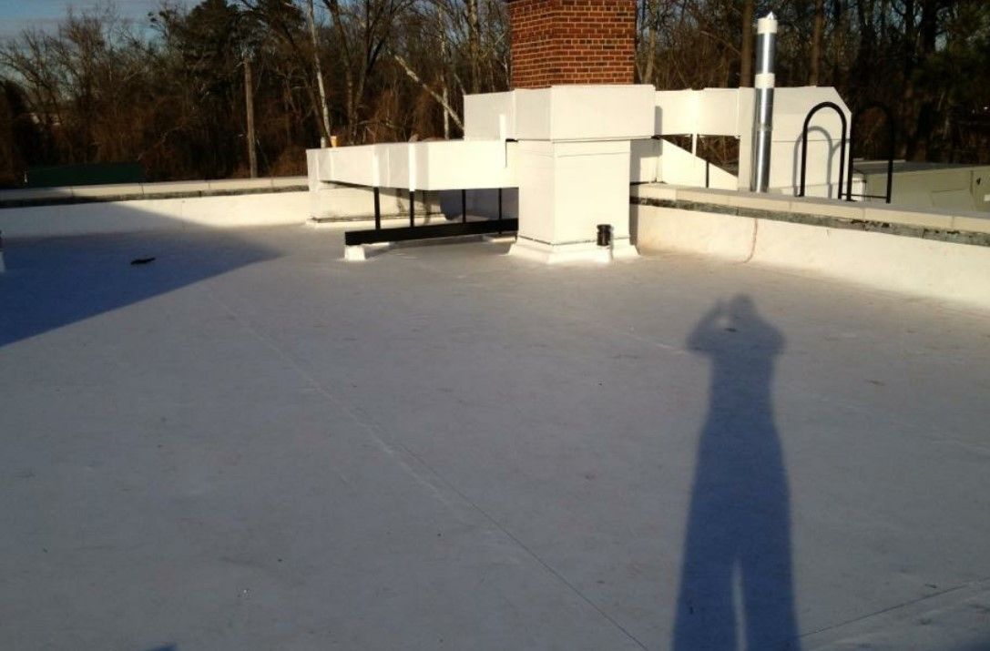 A shadow of a person is cast on a white roof.