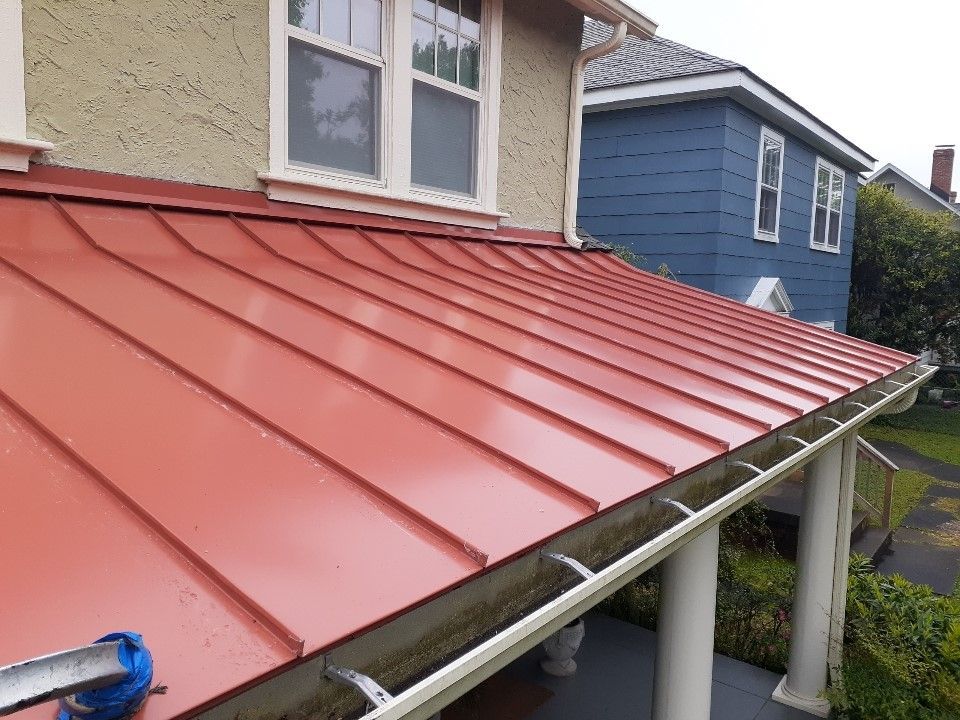 A red metal roof is on the side of a house.
