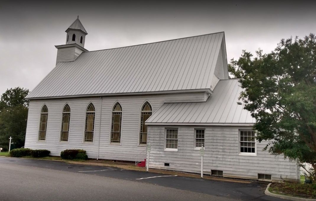 A white church with a metal roof and a steeple