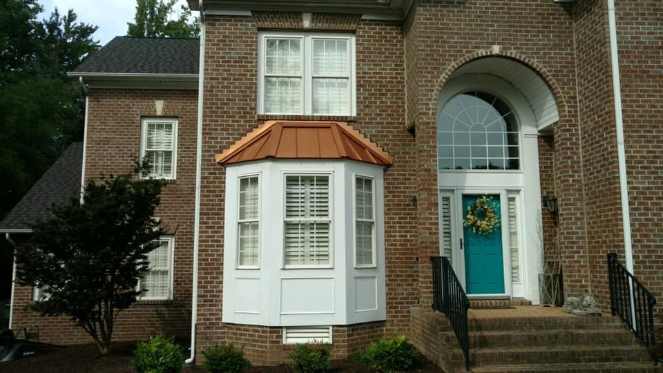 A brick house with a blue door and a bay window