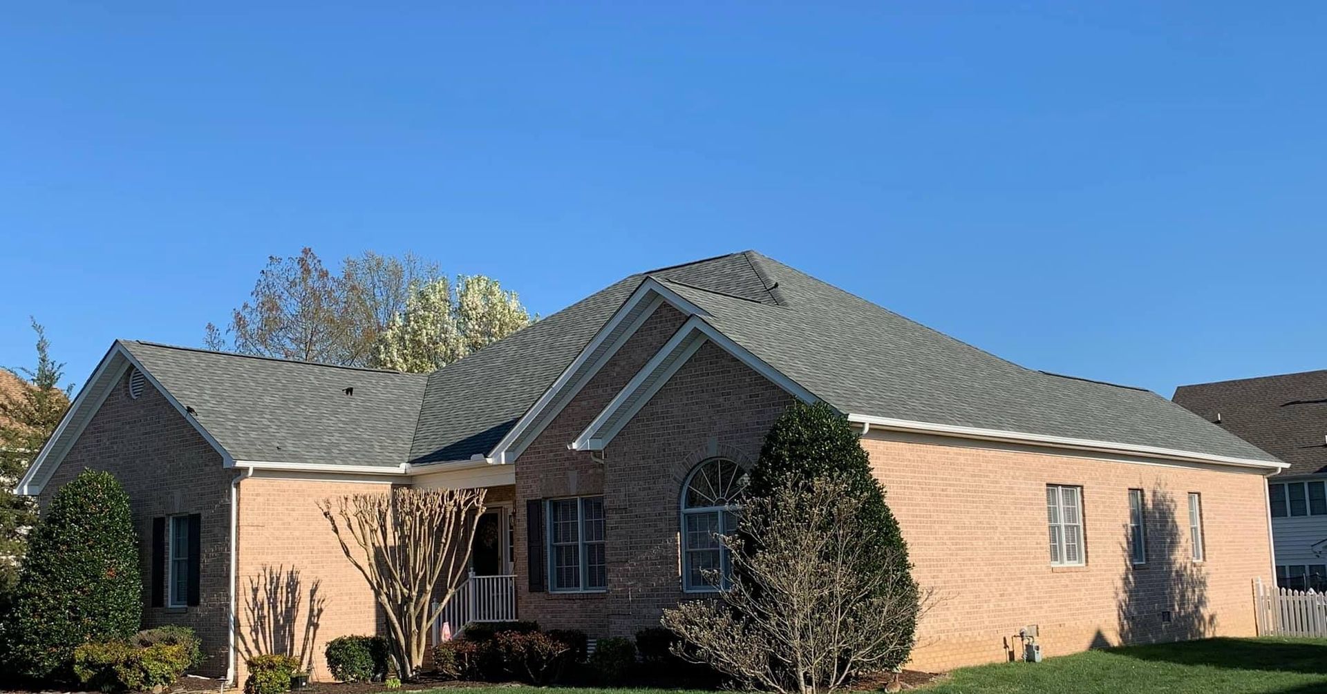 A brick house with a gray roof and a blue sky in the background