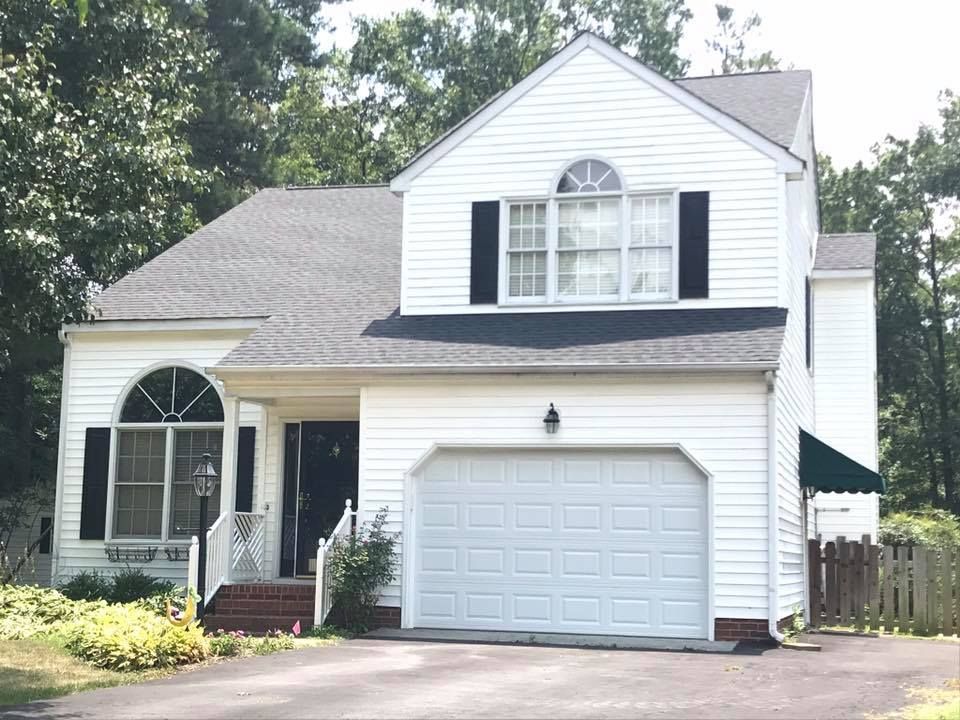 A white house with black shutters and a white garage door