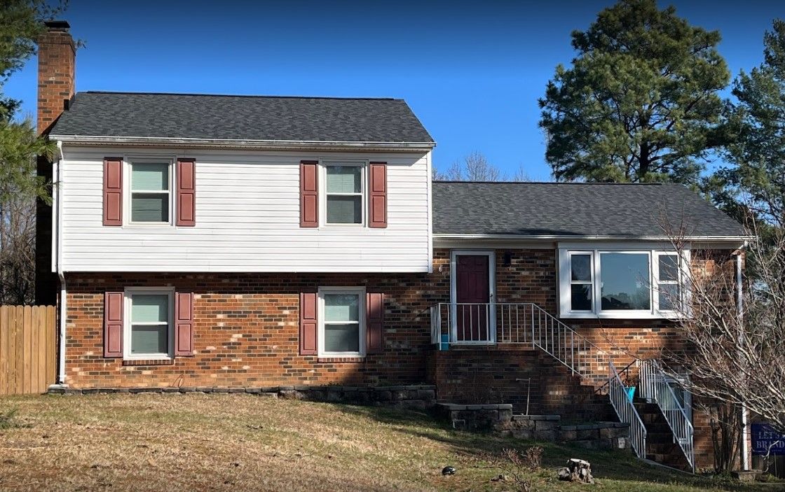 A large brick house with a white siding and red shutters.