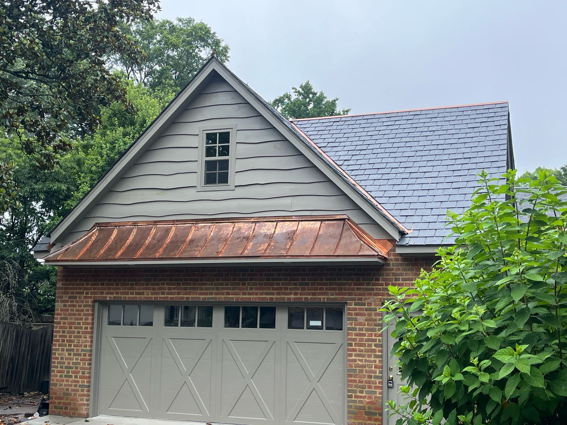 A brick garage with a copper roof and a window.