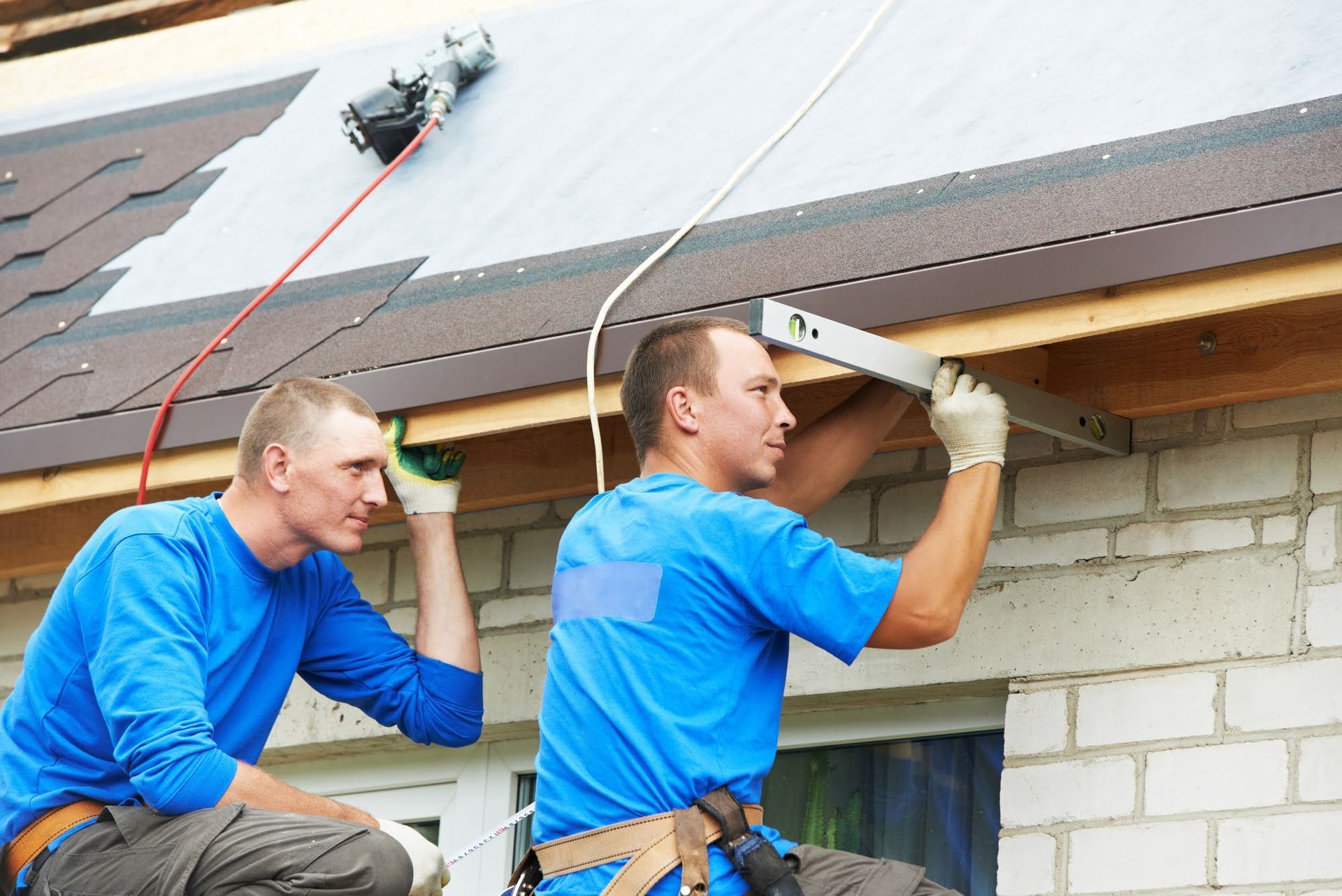 Two men are working on the roof of a house.