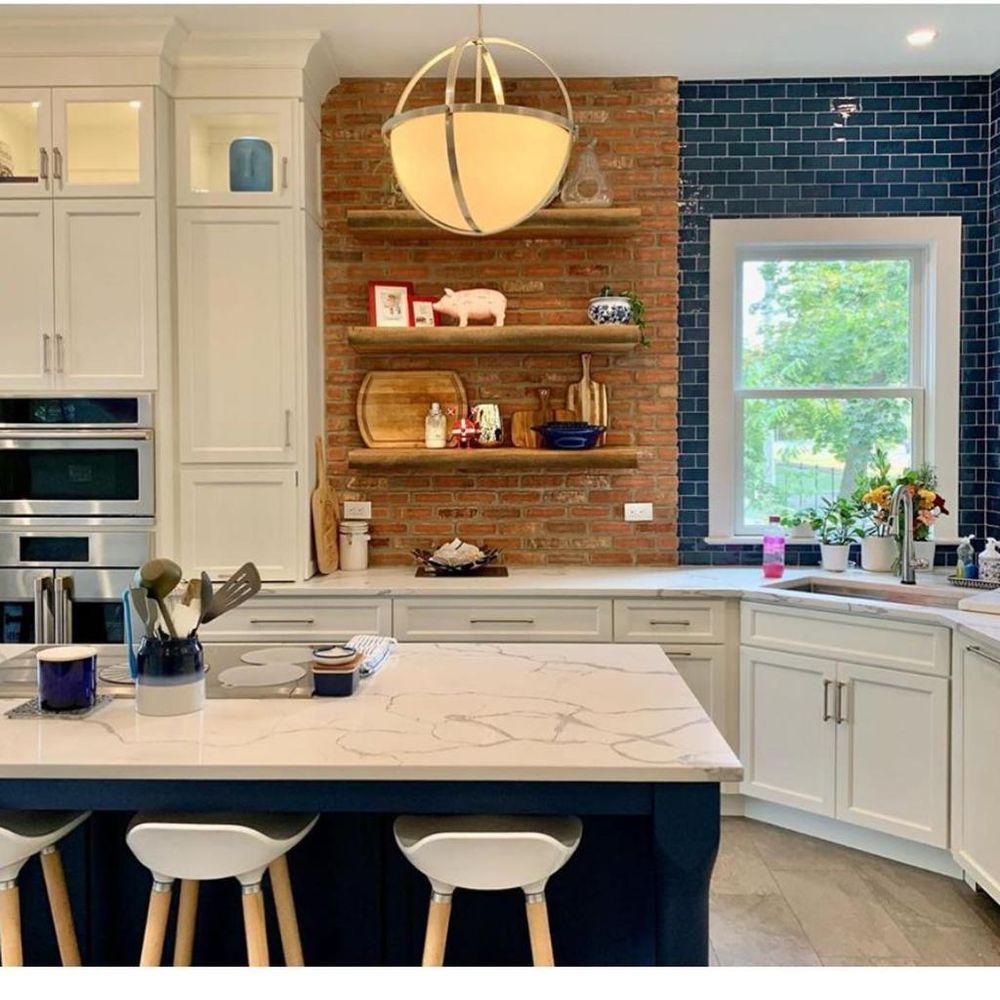 A kitchen with white cabinets and a brick wall