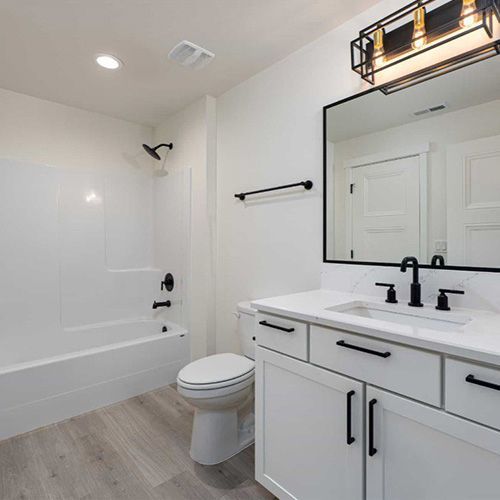 A bathroom with a toilet , sink , bathtub and mirror.