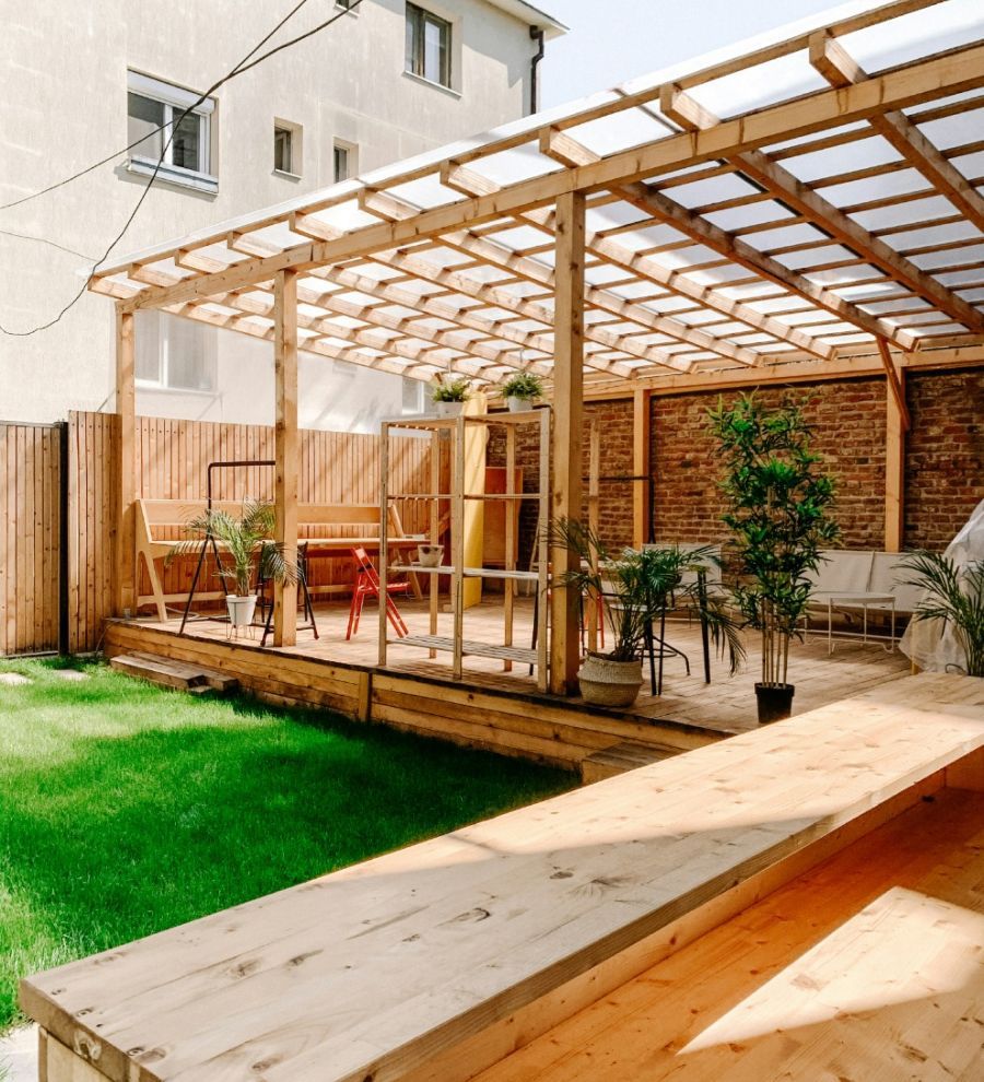 A wooden patio with a clear roof and a brick wall