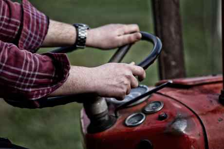 Le mani dell'agricoltore sul volante del trattore