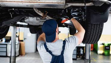 A man is working under a car in a garage.