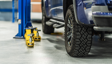 A blue truck is sitting on a lift in a garage.