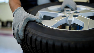 A person is putting a tire on a car wheel.