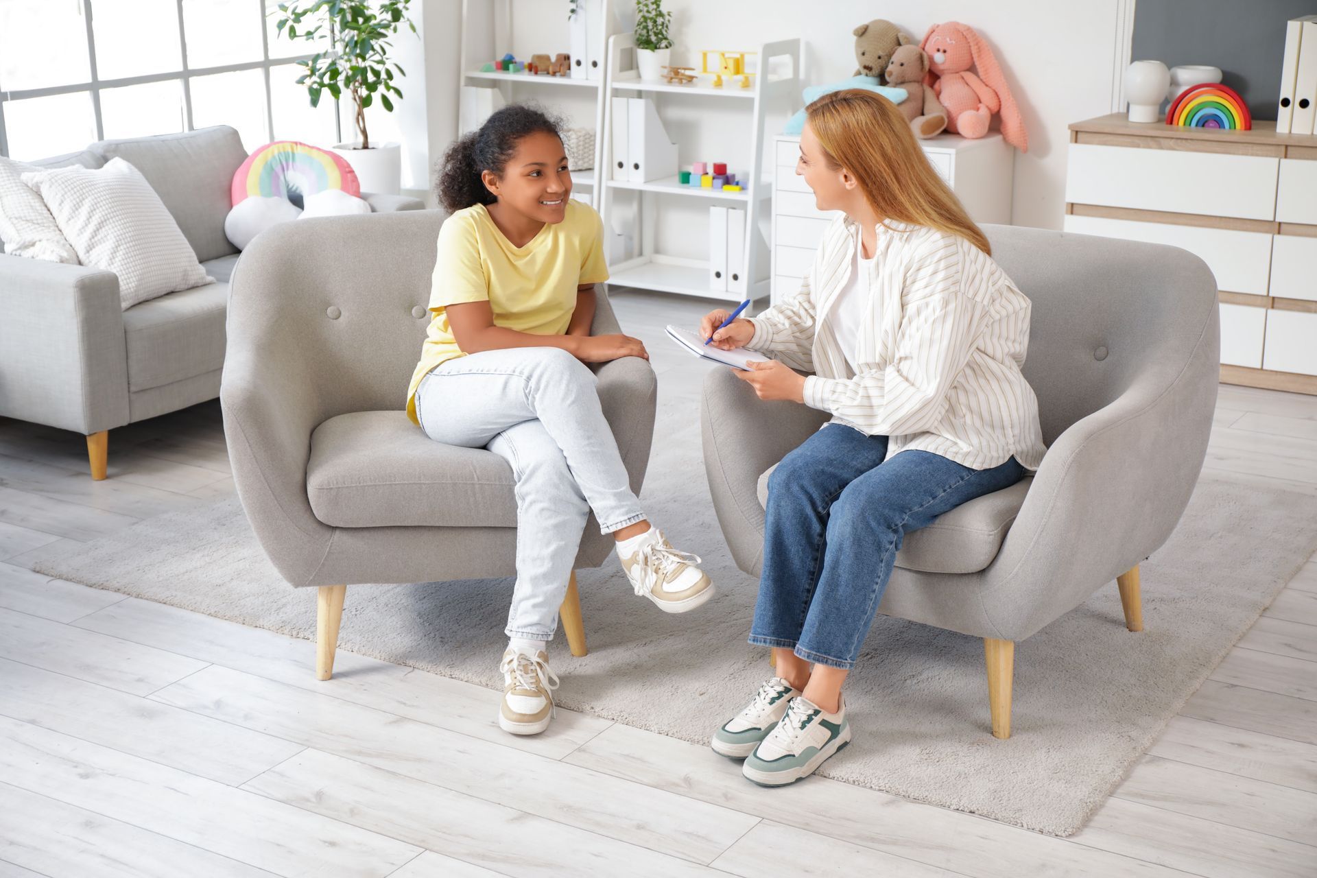 A woman is sitting on a couch talking to a young girl.