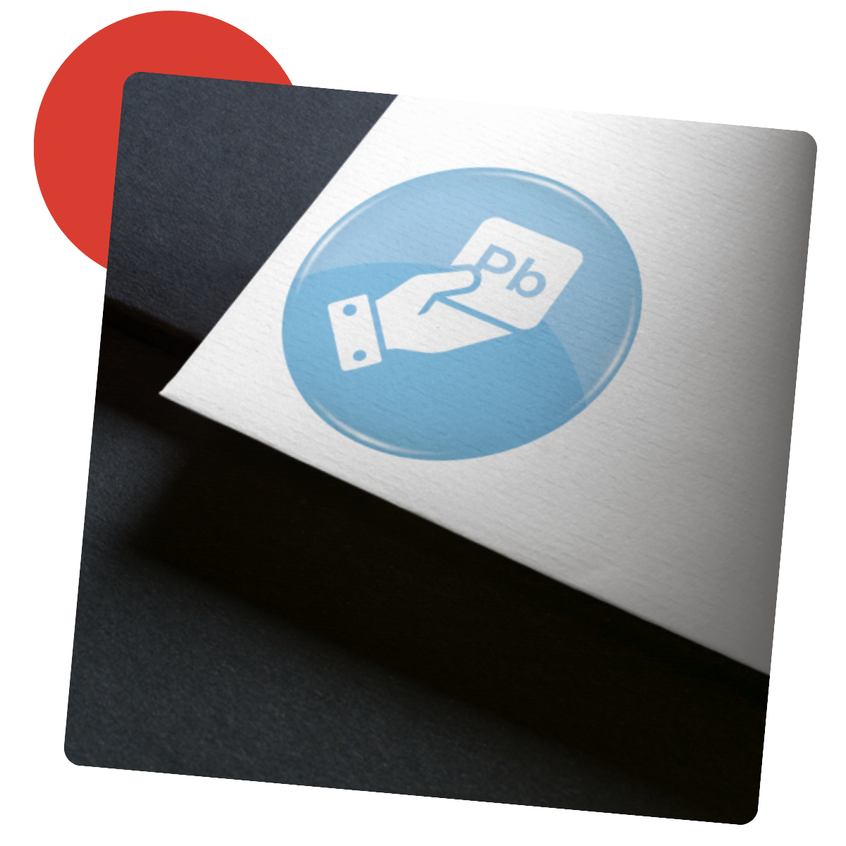 Main tenant une carte avec le symbole de l'élément Pb, à l'intérieur d'un cercle bleu sur fond blanc et noir, avec un cercle rouge dans le coin supérieur gauche.