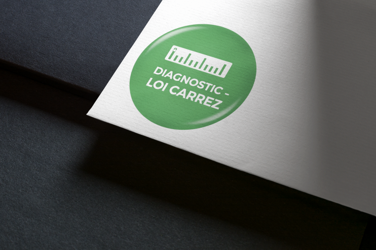 Autocollant circulaire vert avec texte blanc et un dessin de règle sur papier blanc, en biais sur une surface gris foncé.