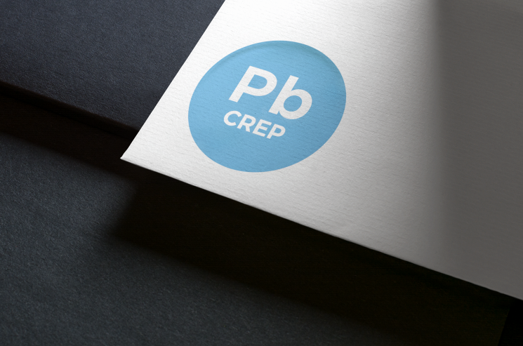 Logo de « Pb CREP » dans un cercle bleu clair, sur une carte blanche. La carte repose sur une surface sombre.