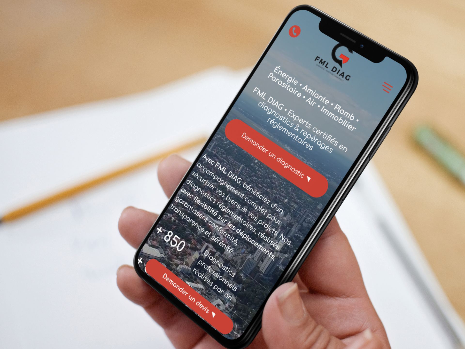 Une personne tenant un smartphone affichant un site web avec un logo rouge et blanc et un texte concernant des services financiers.