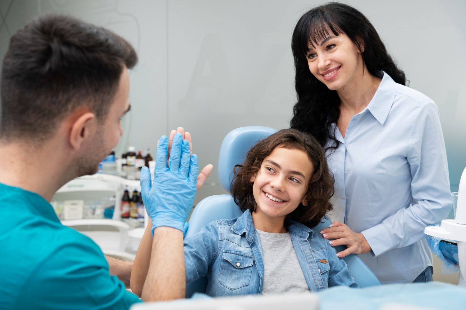 A woman is putting toothpaste on a little girl 's finger.