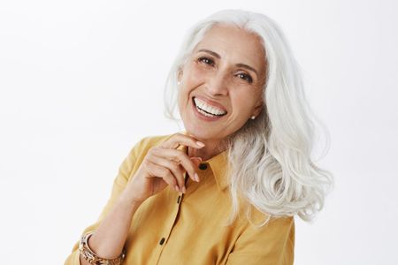 An elderly woman in a red sweater is eating something.