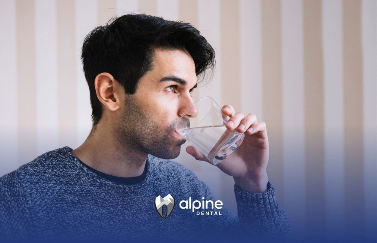 Man drinking a glass of water indoors.