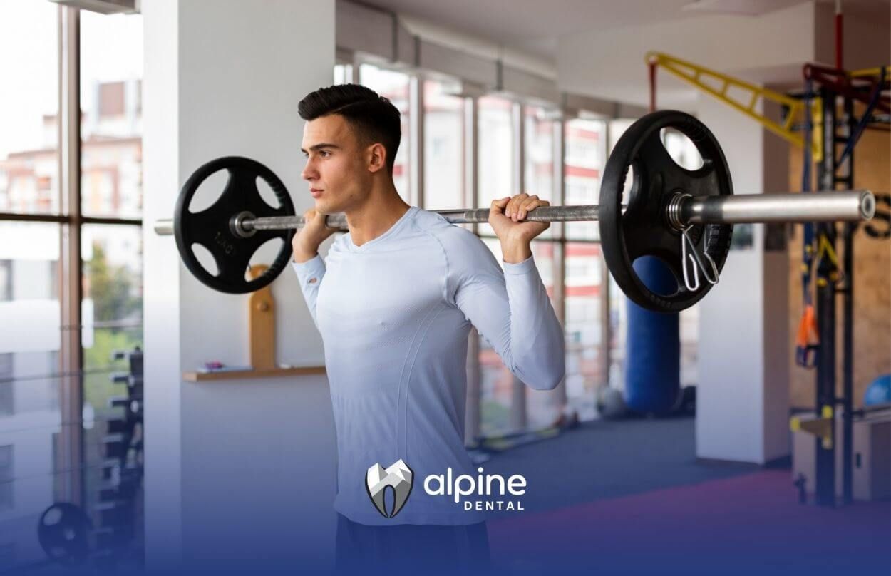 A man is squatting with a barbell on his shoulders in a gym.